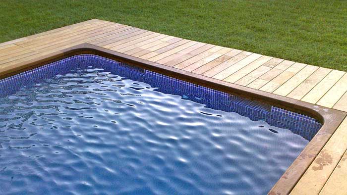 Piscina de obra con madera y cesped natural